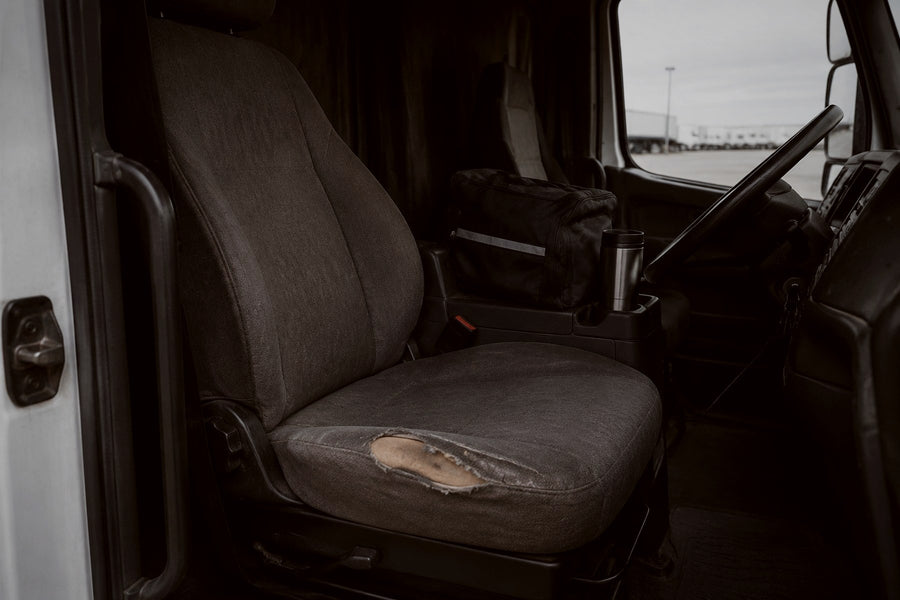 Worn company fleet truck seat with a duffel bag and travel mug